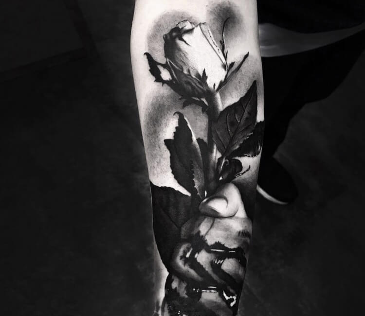 Black rose tattoo on the forearm.