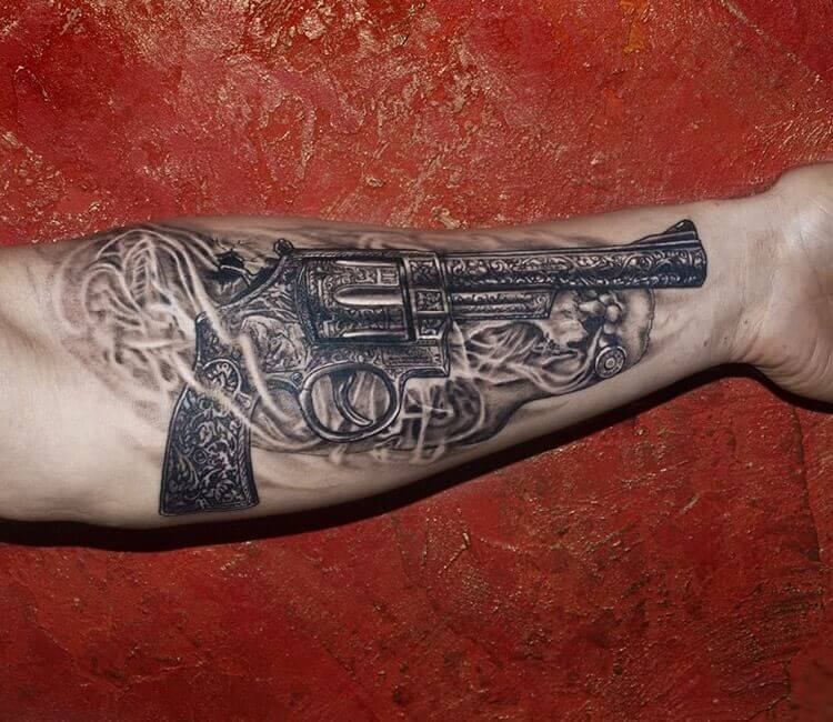 Small fine line style revolver tattoo on the left inner