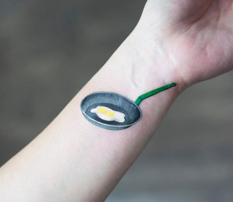Coffee cup and fried egg tattoo on the right inner arm